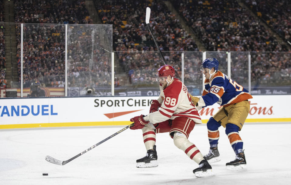 Calgary Flames' Ilya Solovyov (98) and Edmonton Oilers' Dylan Holloway (55) battle for the puck during third-period NHL Heritage Classic outdoor hockey game action in Edmonton, Alberta, Sunday, Oct. 29, 2023. (Jason Franson/The Canadian Press via AP)