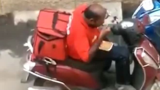 A still taken from a video shared on social media of a Zomato worker tucking in to a customer’s food before resealing the tubs and continuing with his delivery. (Twitter/@madna_chikna)