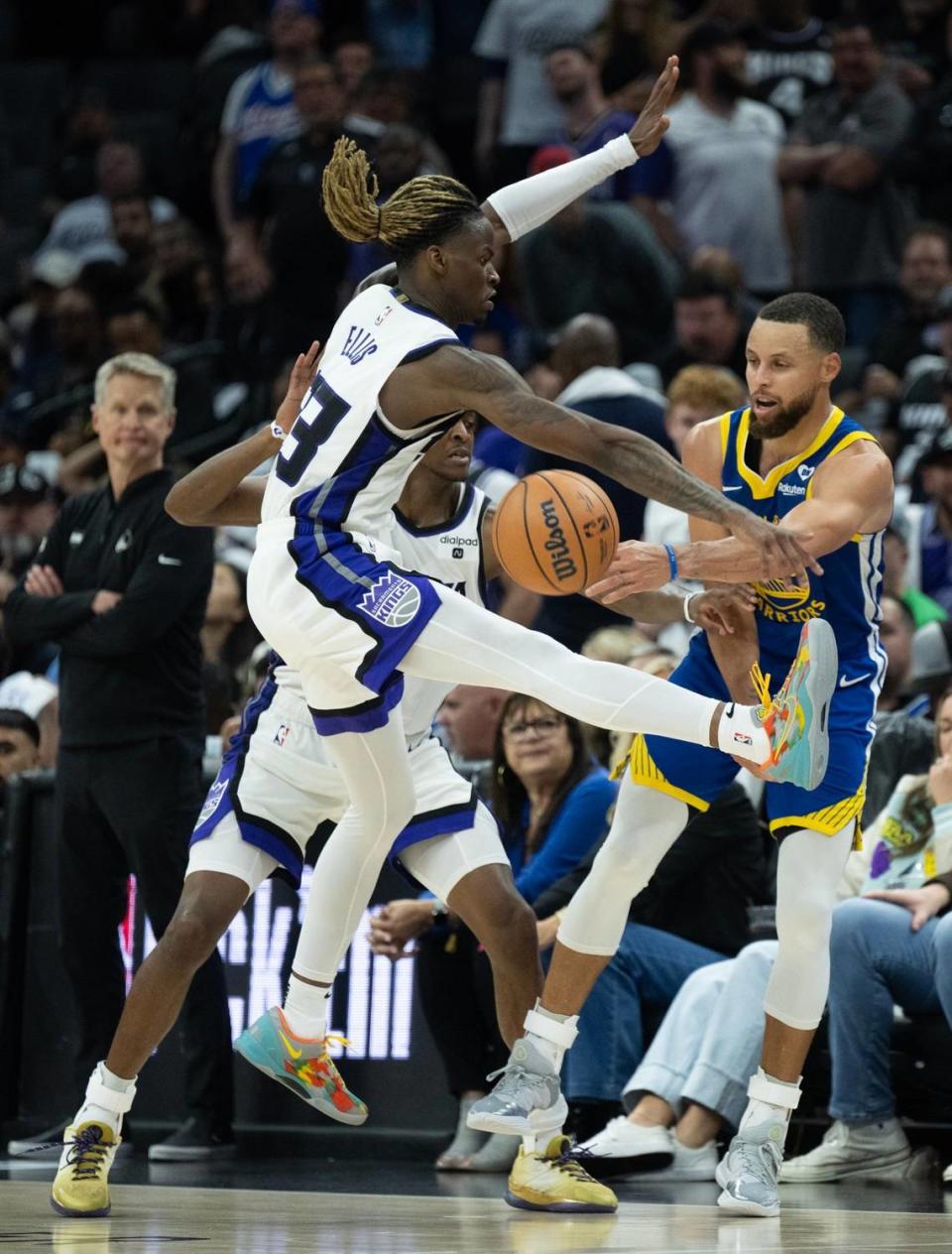 Golden State Warriors guard Stephen Curry (30) passes the ball around Sacramento Kings guards Keon Ellis (23) and De’Aaron Fox (5) on Tuesday.