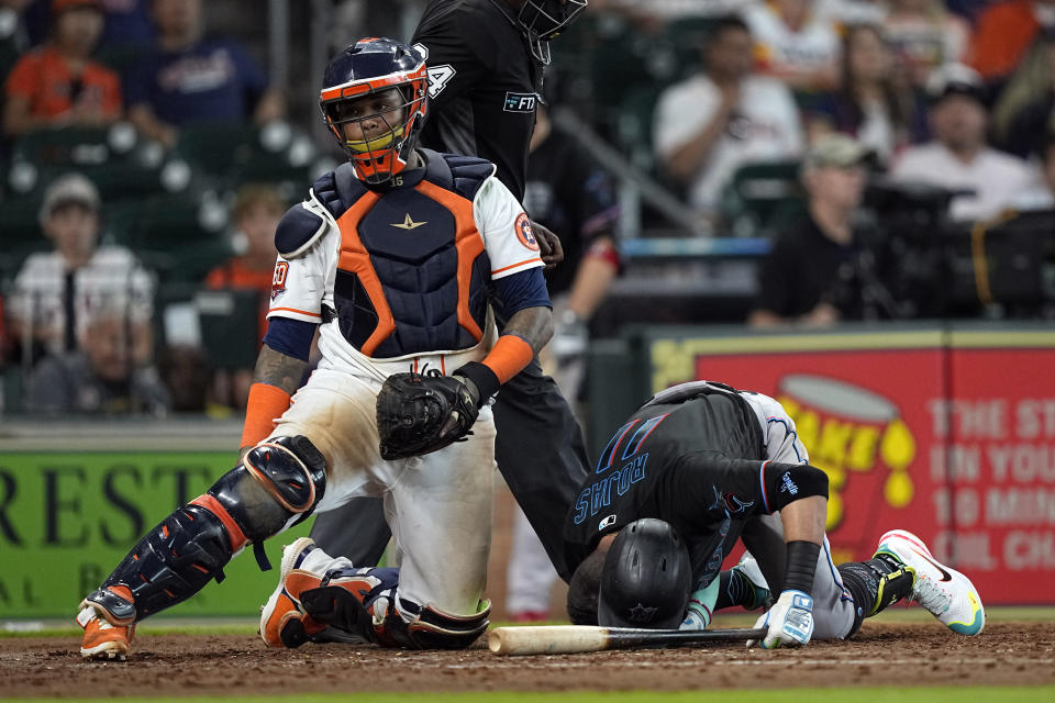 Miami Marlins' Miguel Rojas (11) is slow to get up after being hit by a pitch as Houston Astros catcher Martin Maldonado kneels behind home plate during the sixth inning of a baseball game Saturday, June 11, 2022, in Houston. (AP Photo/David J. Phillip)