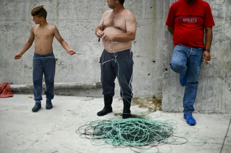 Paulo Miguel (L), 12, prepares a fishing net with his father Jose Vieira (C) at Rabo de Peixe, on Sao Miguel island, in the Portuguese archipelago of Azores