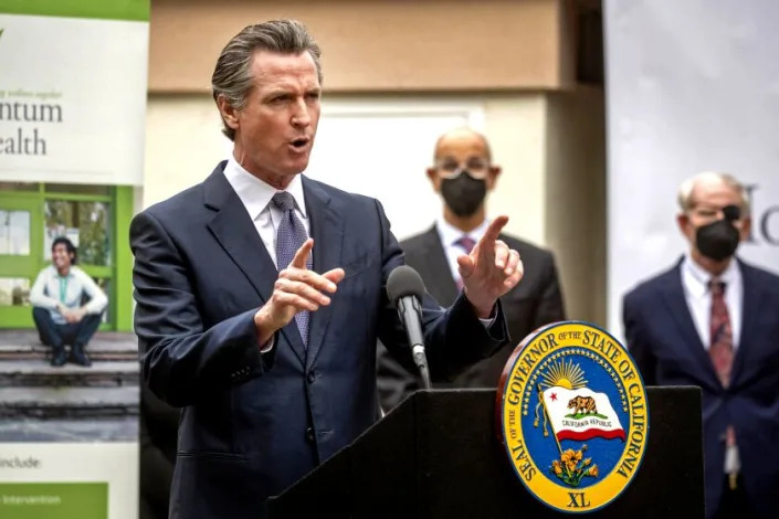 Gov. Gavin Newsom, speaking at a mental health treatment center in San Jose, Calif., announces &quot;Care Court,&quot; a program that would target people suffering from psychosis who have lost their ability to care for themselves, Thursday, March 3, 2022. California's governor is proposing a plan to offer more services to homeless people with severe mental health and addiction disorders even if that means forcing some into care. Newsom was joined by Dr. Mark Ghaly, center, Secretary of the California Health &amp; Human Services and Santa Clara County Judge Stephen Manley. (Karl Mondon/Bay Area News Group via AP)
