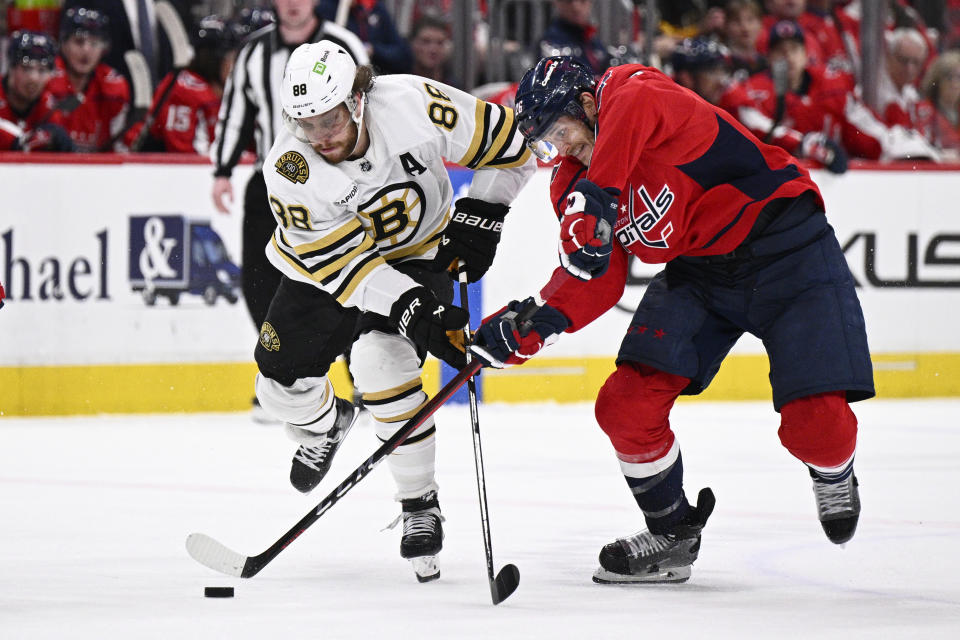 Boston Bruins right wing David Pastrnak (88) and Washington Capitals center Nic Dowd battle for the puck during the second period of an NHL hockey game, Monday, April 15, 2024, in Washington. (AP Photo/Nick Wass)