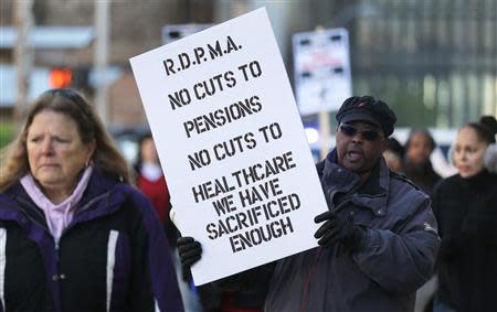 Detroit city workers and retirees carry signs protesting against cuts in their city pensions and health care benefits during a protest against the city's municipal bankruptcy filing, outside the Federal courthouse in Detroit, Michigan October 23, 2013. REUTERS/Rebecca Cook