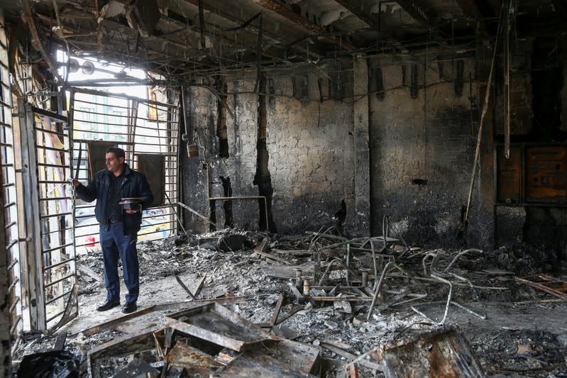 A man inspects the ruins of a bank after protests against increased fuel prices