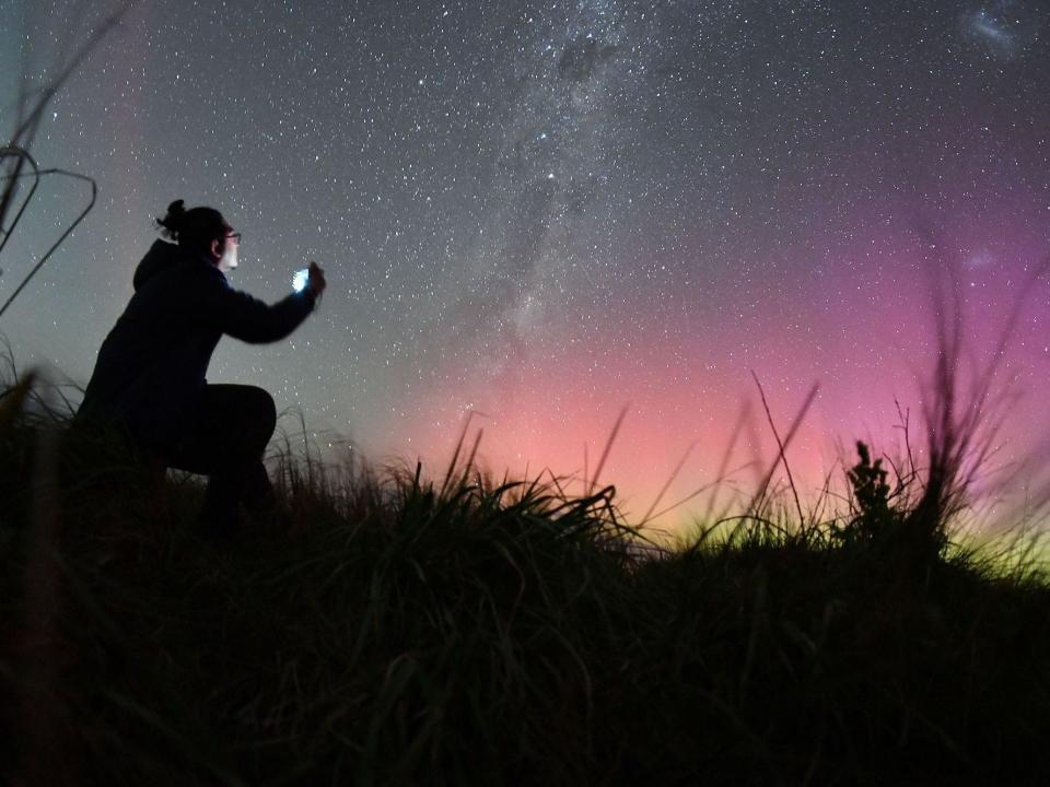a man takes a selfie while lookign at the Southern lights.