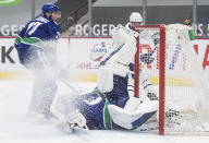 Vancouver Canucks goalie Braden Holtby stops Toronto Maple Leafs' Wayne Simmonds, back right, as Vancouver's Travis Hamonic, back left, watches during the third period of an NHL hockey game in Vancouver, British Columbia, Sunday, April 18, 2021. (Darryl Dyck/The Canadian Press via AP)