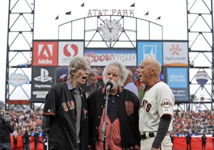 Giants coach Tim Flannery (right) sings the national anthem with the Grateful Dead's Phil Lesh and Bob Weir. (AP)