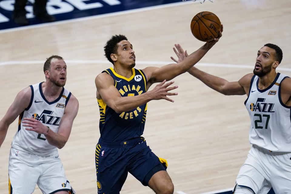 Indiana Pacers guard Malcolm Brogdon (7) shoots between Utah Jazz forward Joe Ingles (2) and center Rudy Gobert (27) during the second half of an NBA basketball game in Indianapolis, Sunday, Feb. 7, 2021. (AP Photo/Michael Conroy)