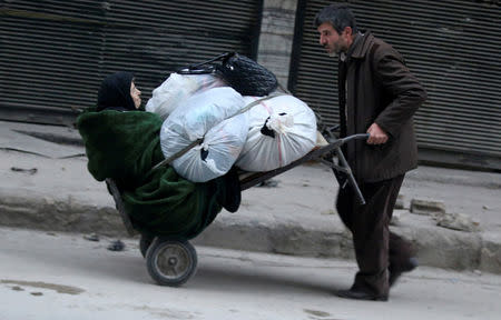 A man pushes a cart carrying an elderly woman and belongings as they flee deeper into the remaining rebel-held areas of Aleppo, Syria. REUTERS/Abdalrhman Ismail