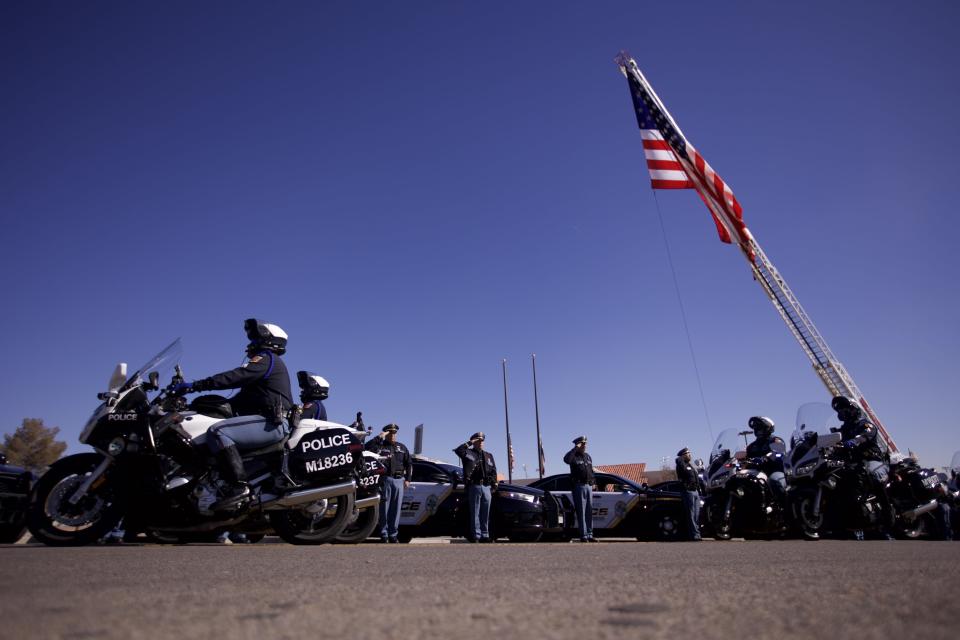 Officers stand outside in salute as the procession for the late El Paso police Chief Greg Allen passes by Mission Valley Regional Command Center.