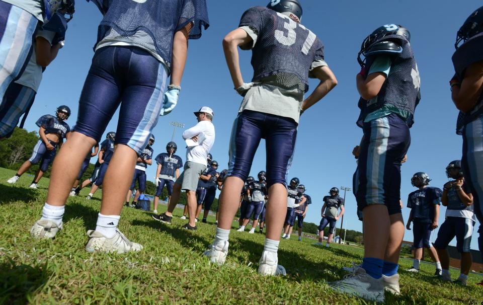 Head coach Robert Lomp talks to his team circled around at a morning practice for the Sandwich High School football team.