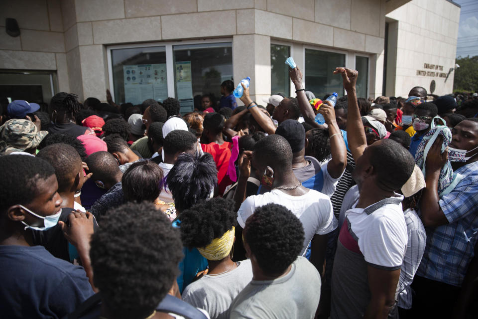 Haitians gather in front of the U.S. Embassy amid rumors on radio and social media that the U.S. will be handing out exile and humanitarian visas, in Port-au-Prince, Haiti, Friday, July 9, 2021, two days after President Jovenel Moise was assassinated in his home. (AP Photo/Joseph Odelyn)