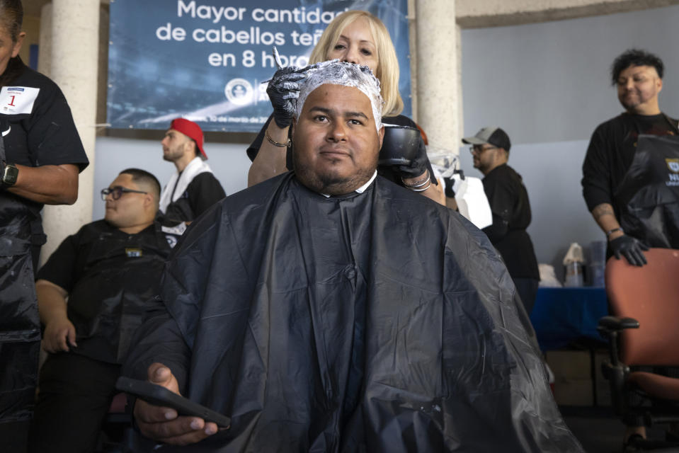 A fan of the Puerto Rico baseball team gets his hair bleached as part of a mass hair dying event in an attempt to break the Guinness World Record for the most hair dyed in eight hours in Guaynabo, Puerto Rico, Friday, March 10, 2023. Going blond, which began as a joke among team members playing in California many years ago, was set up by fans to show support for their team competing at the World Baseball Classic. (AP Photo/Alejandro Granadillo)