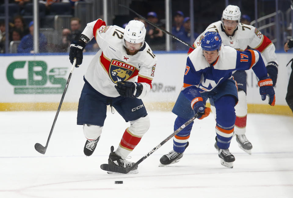 Florida Panthers forward Jonah Gadjovich (12) and New York Islanders forward Matt Martin (17) skate to the puck during the first period of an NHL hockey game Saturday, Jan. 27, 2024, in Elmont, N.Y. (AP Photo/John Munson)