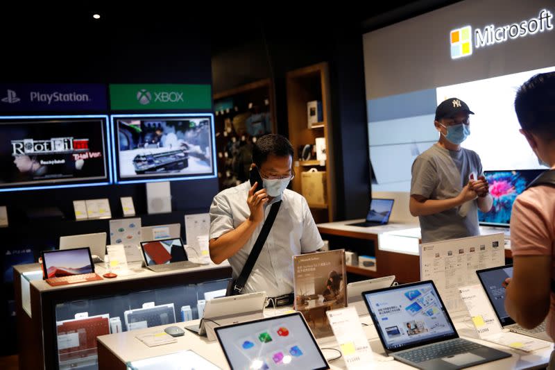 Men wearing face masks look at the merchandise on an electronics store at a shopping mall, in Beijing