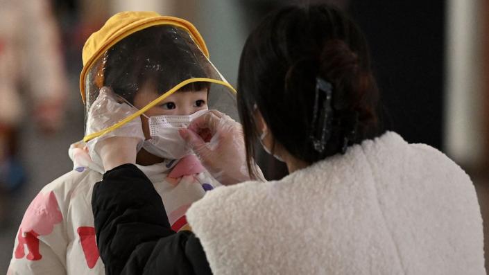 A woman arranges a face mask on a child's face at the international airport in Beijing.