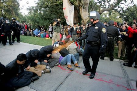 A University of California Davis police officer pepper-sprays students during their sit-in at an "Occupy UCD" demonstration in Davis, California November 18, 2011. REUTERS/Brian Nguyen
