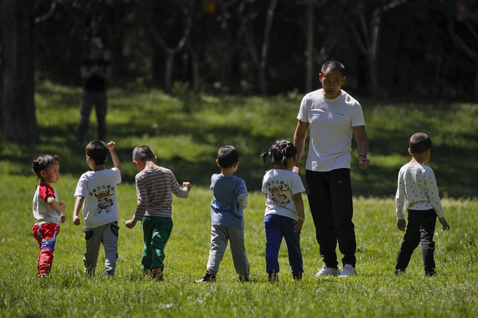 Children accompanied by a man play at a public park as kindergarten and primary schools still remain closed following the new coronavirus outbreak in Beijing, Monday, May 11, 2020. China reported another rise in coronavirus cases Monday, amid government reminders for people to "remain alert and step up personal protection against the virus." (AP Photo/Andy Wong)
