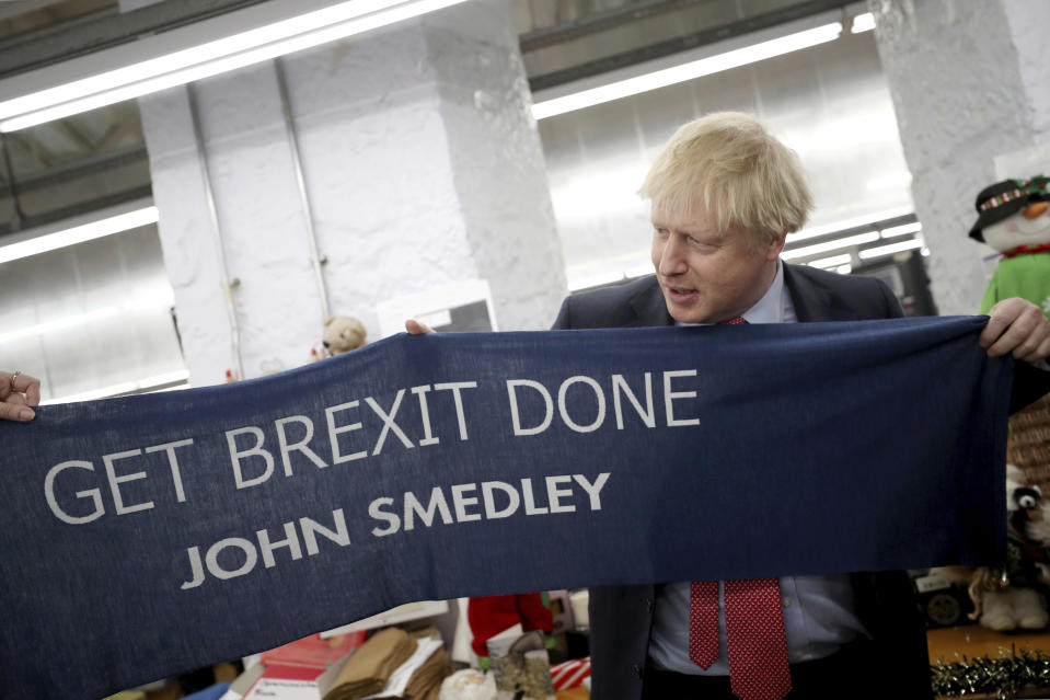 Britain's Prime Minister Boris Johnson hold a scarf with slogan "Get Brexit Done" as he visits John Smedley Mill in Matlock, England, Thursday, Dec. 5, 2019. Britain is holding a general election a week from now and fractures are emerging within jittery political parties unsure how a volatile electorate will judge them. Conservative Prime Minister Boris Johnson and main opposition Labour Party leader Jeremy Corbyn both faced criticism of their moral character. (Hannah McKay/Pool Photo via AP)