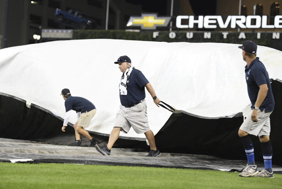Members of the Detroit Tigers grounds crew cover the field with storms approaching after the sixth inning of the team's baseball game against the Milwaukee Brewers in Detroit, Tuesday, Sept. 14, 2021. (AP Photo/Lon Horwedel)