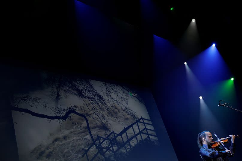 Violinist Simon Garcia plays an adaptation of Antonio Vivaldi's 'The Four Seasons' concertos as a screen shows flooding on International Day against Climate Change, Madrid.