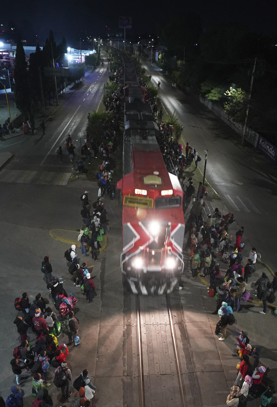 Migrants stand alongside a rail track as a northbound freight train pulls into Irapuato, Mexico, Saturday, Sept. 23, 2023. (AP Photo/Marco Ugarte)