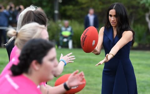 The Duchess of Sussex throws an Australian Rules football during a reception in Melbourne - Credit: Julian Smith/AFP