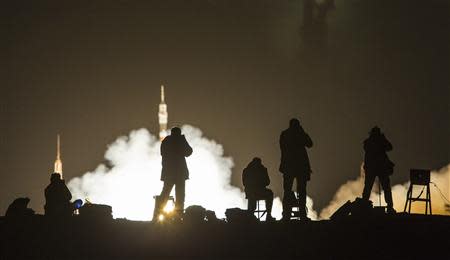 Photographer take pictures as the Soyuz TMA-10M spacecraft carrying the International Space Station (ISS) crew of U.S. astronaut U.S. astronaut Michael Hopkins, Russian cosmonauts Oleg Kotov and Sergey Ryazanskiy blasts off from the launch pad at the Baikonur cosmodrome September 26, 2013. REUTERS/Shamil Zhumatov