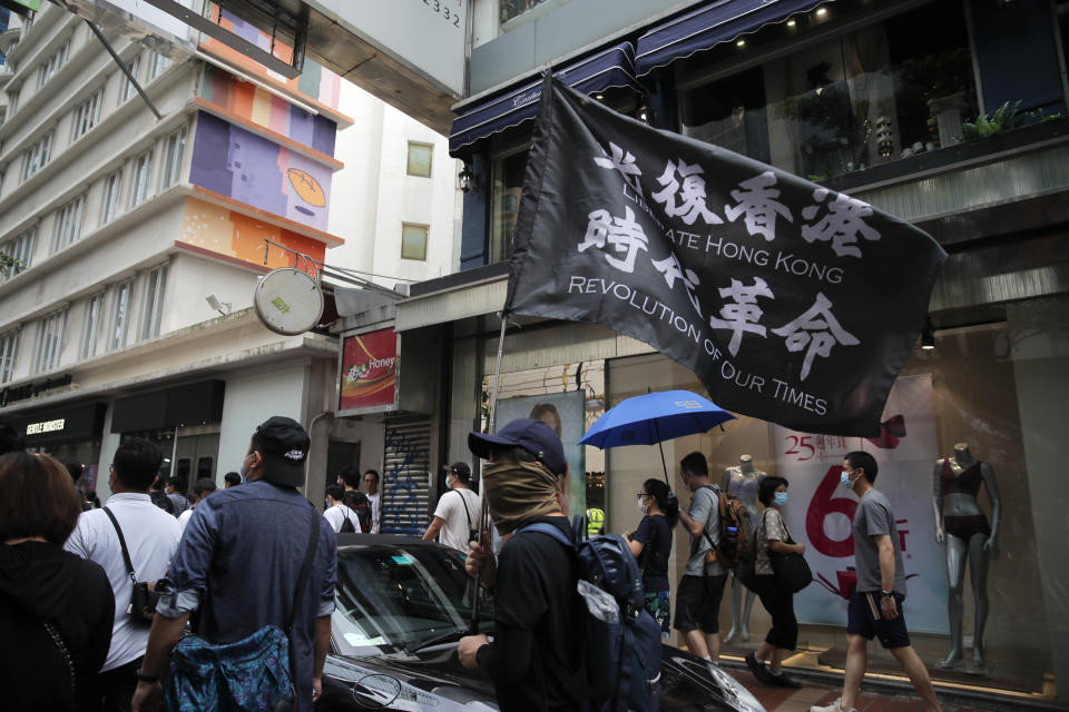 Protesters carry the flag which reads "Liberate Hong Kong, revolution of our time" in Causeway Bay before the annual handover march in Hong Kong, Wednesday, July 1, 2020. Hong Kong marked the 23rd anniversary of its handover to China in 1997, and just one day after China enacted a national security law that cracks down on protests in the territory. (AP Photo/Kin Cheung)