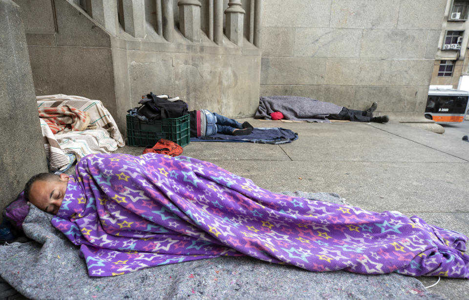 En esta foto del jueves 7 de mayo de 2020, personas sin hogar duermen afuera de la catedral de Sao Paulo, Brasil. (AP Foto/André Penner)