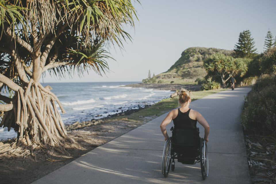 Pictured is a paraplegic woman travelling in her wheelchair beside the ocean.