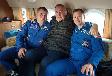 Head of Russian space agency Roscosmos Dmitry Rogozin (C) poses with astronauts Alexey Ovchinin of Russia and Nick Hague of the U.S., who survived the mid-air failure of a Russian rocket, on onboard a plane during a flight to Chkalovsky airport near Star City outside Moscow, Russia October 12, 2018. Russian space agency Roscosmos/Handout via REUTERS.
