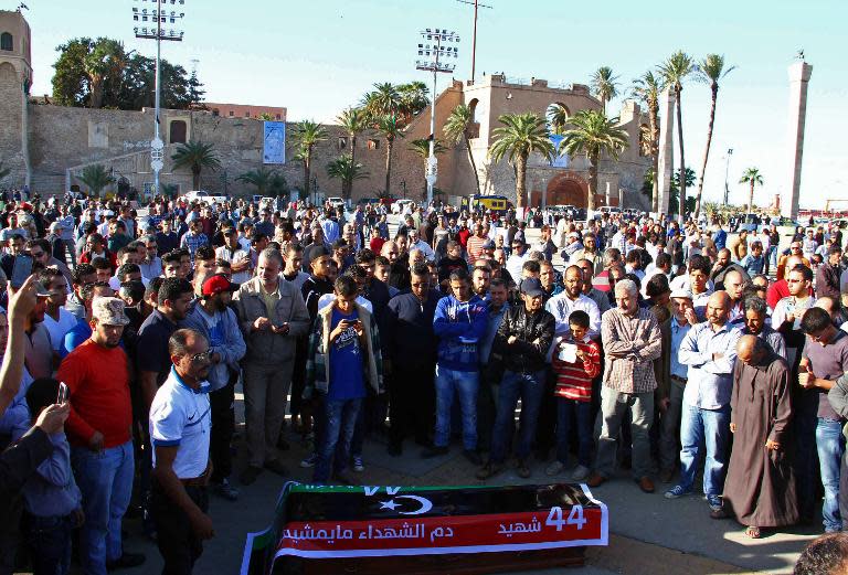 Mourners stand around the coffin, draped in the Libyan flag, of one of the victims of a shootout the previous day at an anti-militia protest in the Libyan capital, Tripoli, on November 16, 2013