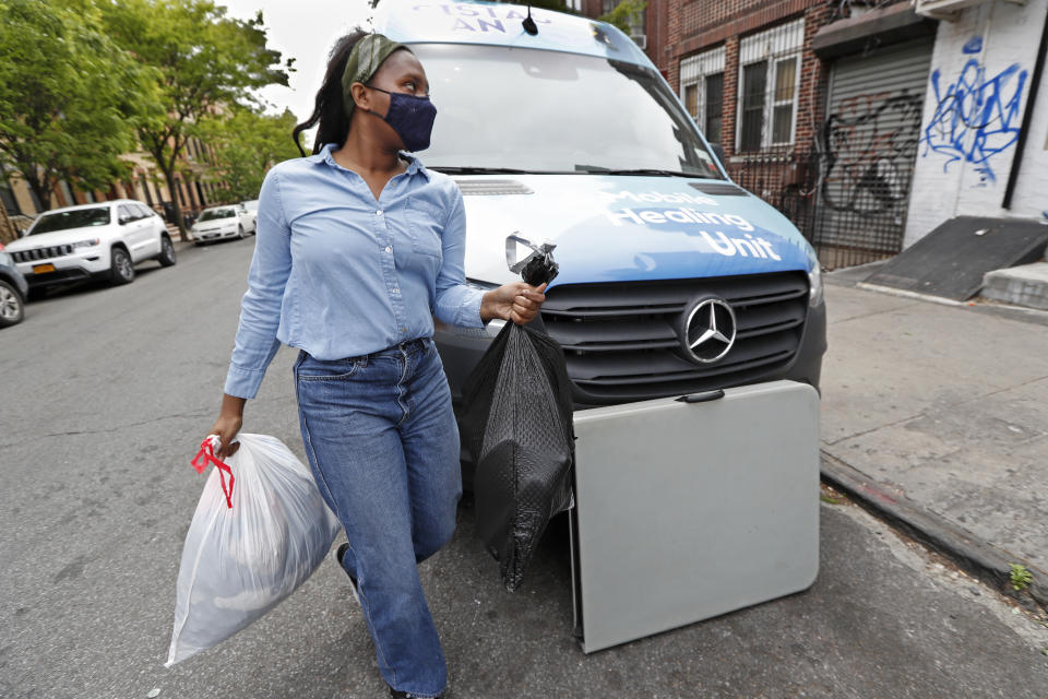 Black Women's Blueprint intern Shabieko Ivy carries bags of donated clothing destined for the Bushwick Mutual Aid group to a bookstore, distributing them to members of the community in need amid the coronavirus outbreak, Tuesday, May 19, 2020, in New York. Launched a year earlier by the nonprofit Black Women's Blueprint to help survivors of sexual and reproductive violence and physical abuse, during the coronavirus outbreak the women's network has focused on delivering badly-needed resources to black and Hispanic communities, which have had some of the city's highest rates of contagion and death from the virus. (AP Photo/Kathy Willens)