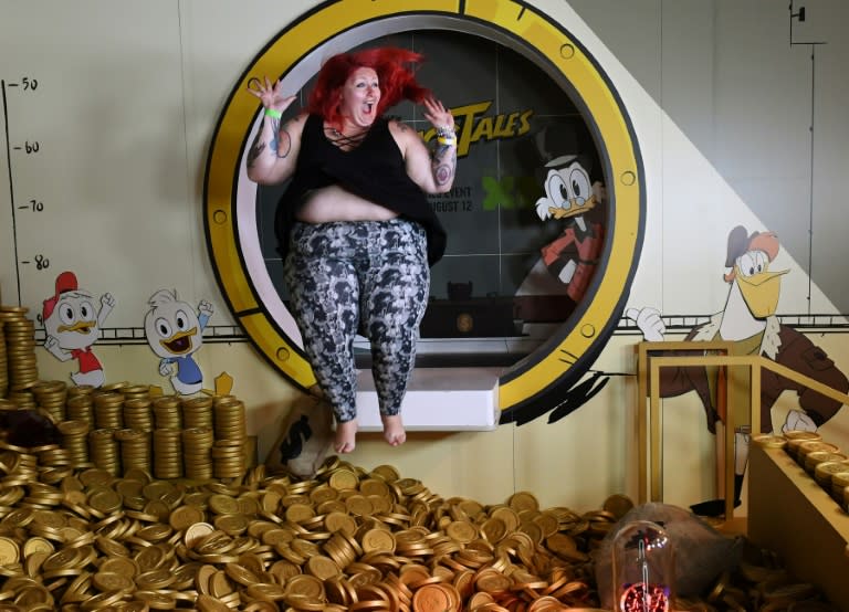 A woman jumps into the money pit at the Duck Tales exhibit at the D23 expo