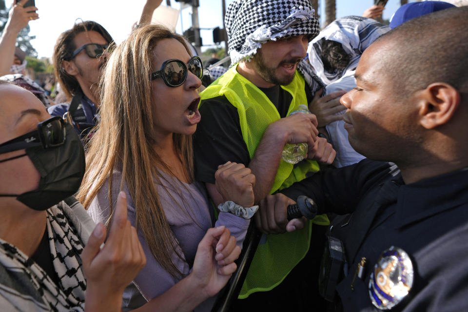 A Los Angeles Police Department officer holds back pro-Palestinian demonstrators at the Shrine Auditorium where a commencement ceremony for graduates from Pomona College was being held Sunday, May 12, 2024, in Los Angeles. (AP Photo/Ryan Sun)