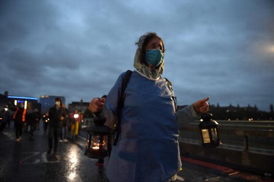 People wearing face masks and holding lanterns attend a vigil for the victims of the coronavirus on Westminster Bridge on 3 July 2020 in London, England (Photo by Chris J Ratcliffe/Getty Images)