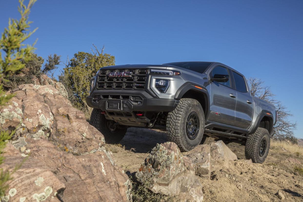 front 34 view of the 2024 gmc canyon at4x aev edition climbing a rock