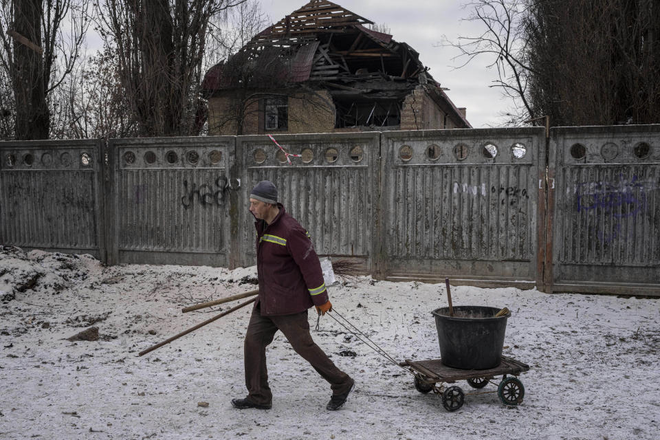 A municipal worker walks in front of a tax office building that have been heavily damaged by a Russian attack in Kyiv, Ukraine, Wednesday, Dec. 14, 2022. (AP Photo/Evgeniy Maloletka)