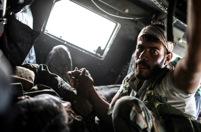 A member of the Syrian Democratic Forces comforts his wounded comrade Ibrahim who was shot by a jihadist sniper as they drive towards a medical centre on the eastern frontline of Raqa