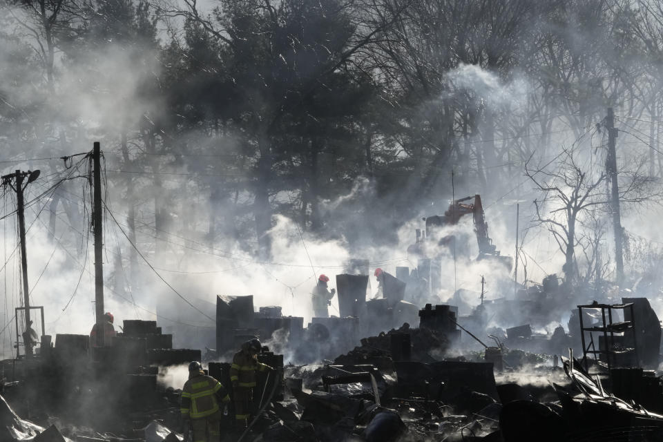 Firefighters clean up the site of a fire at Guryong village in Seoul, South Korea, Friday, Jan. 20, 2023. A fire spread through a neighborhood of densely packed, makeshift homes in South Korea's capital Friday morning. (AP Photo/Ahn Young-joon)