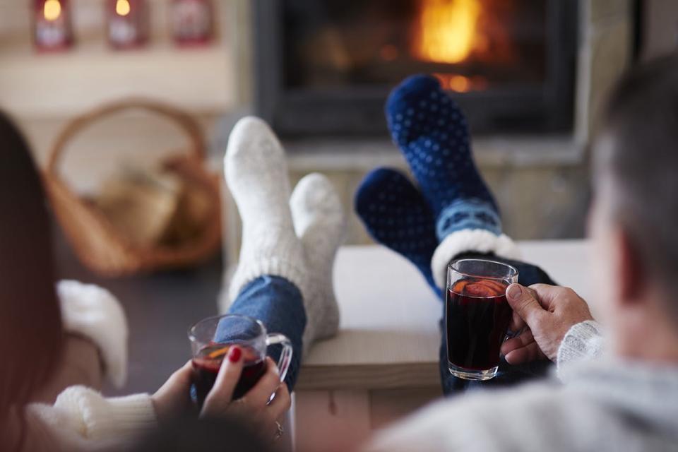 Couple sits by fire with mulled wine