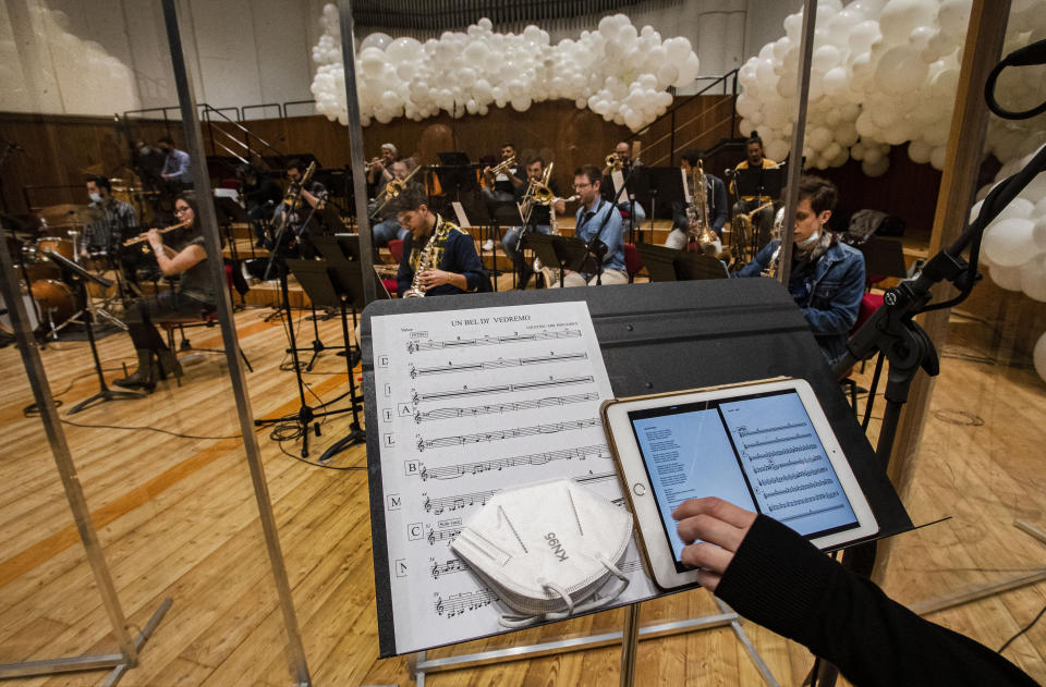 Giuseppe Verdi jazz orchestra musicians and singers play their instruments behind a transparent panel to curb the spread of COVID-19 during a rehearsal at the Giuseppe Verdi Music Conservatory, in Milan, Italy, Friday, May 7, 2021. Whatever the instrument, flute, violin or drums, students at Italy's oldest and largest music conservatory have been playing behind plexiglass screens during much of the pandemic as the Conservatory found ways to preserve instruction throughout Italy’s many rolling lockdowns. (AP Photo/Antonio Calanni)