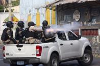 A National Police officer fires tear gas at protesters who are demanding the resignation of Haitian President Jovenel Moise near the presidential palace in Port-au-Prince, Haiti, Tuesday, Feb. 12, 2019. Protesters are angry about skyrocketing inflation and the government's failure to prosecute embezzlement from a multi-billion Venezuelan program that sent discounted oil to Haiti. (AP Photo/Dieu Nalio Chery)