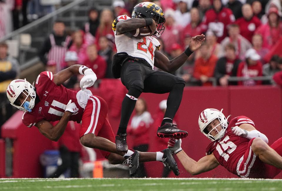 Wisconsin cornerback Alexander Smith (11) and safety John Torchio (15) team up to stop Maryland running back Roman Hemby (24) after a reception during the third quarter of their game Saturday, November 5, 2022 at Camp Randall Stadium in Madison, Wis.