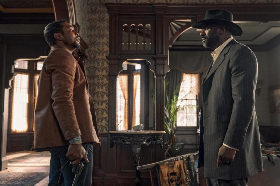 This image released by Netflix shows Jonathan Majors, left, and Idris Elba in a scene from “The Harder They Fall.” (David Lee via AP)