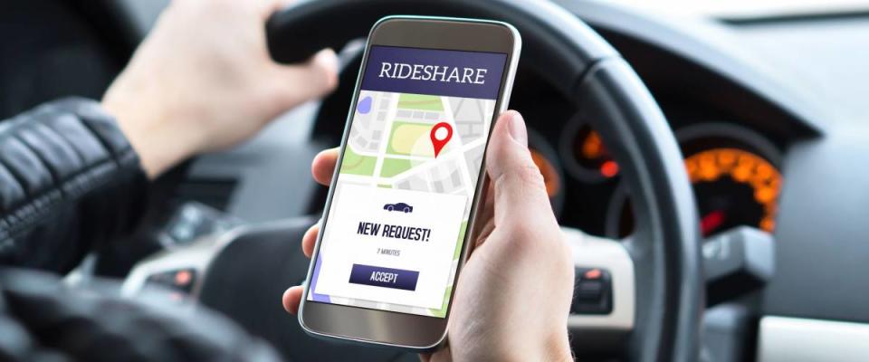 Ride share driver in car using the rideshare app in mobile phone. New taxi ride request from customer in smartphone application. Man picking up passengers for online carpool service.