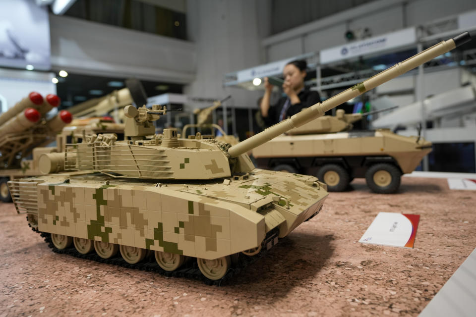 A woman takes a picture of models of battle tanks, displayed at the 11th International Armament and Military Equipment Fair – PARTNER 2023, in Belgrade, Serbia, Monday, Sept. 25, 2023. (AP Photo/Darko Vojinovic)