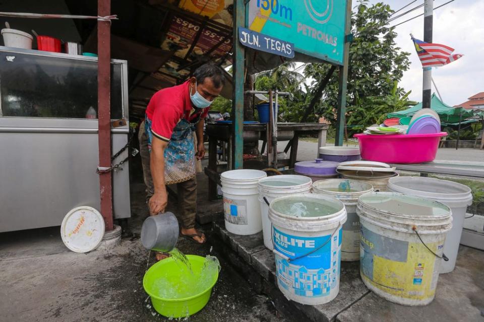 A worker fills a plastic container with water amid water supply disruption in Kampung Jawa, Klang. — Picture by Yusof Mat Isa